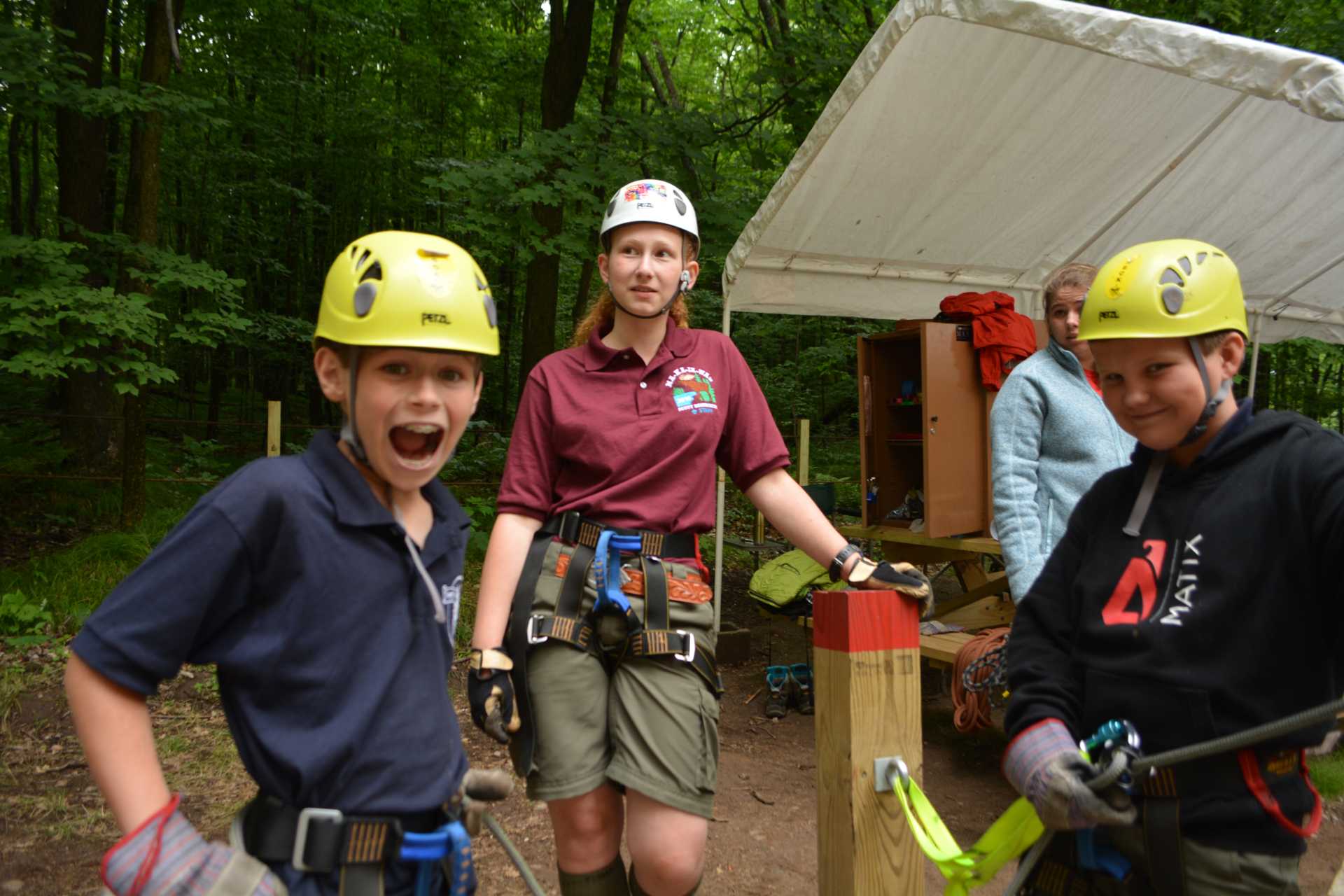 Some scouts near the climbing wall, wearing safety gear, smiling
