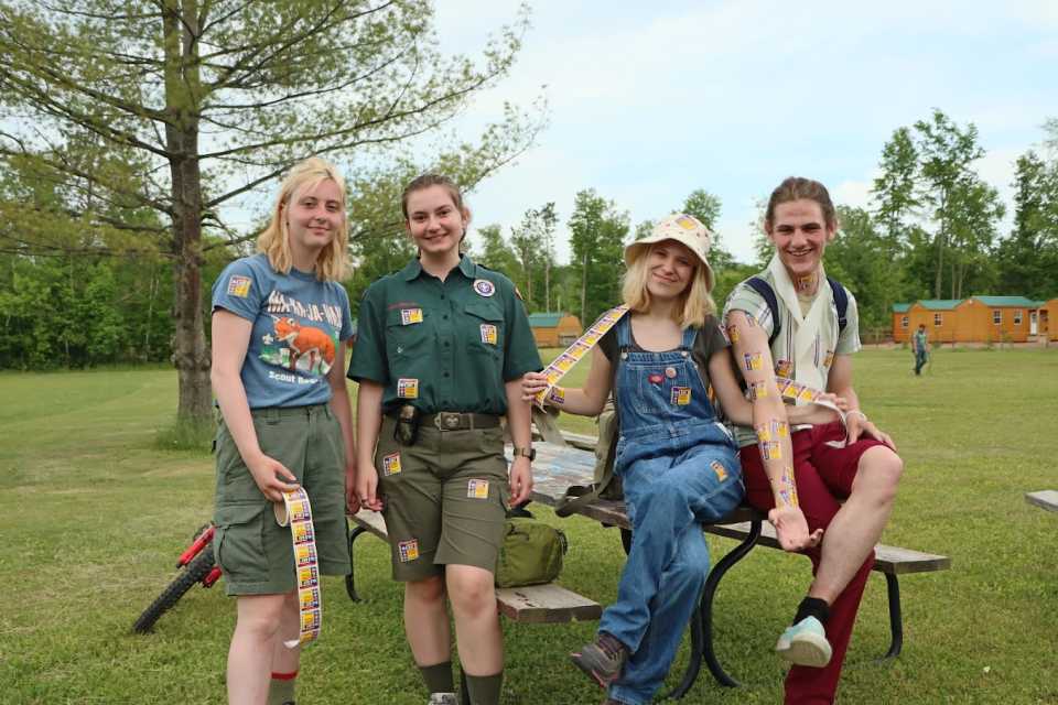 A few girls hang out on a park table, smiling happily